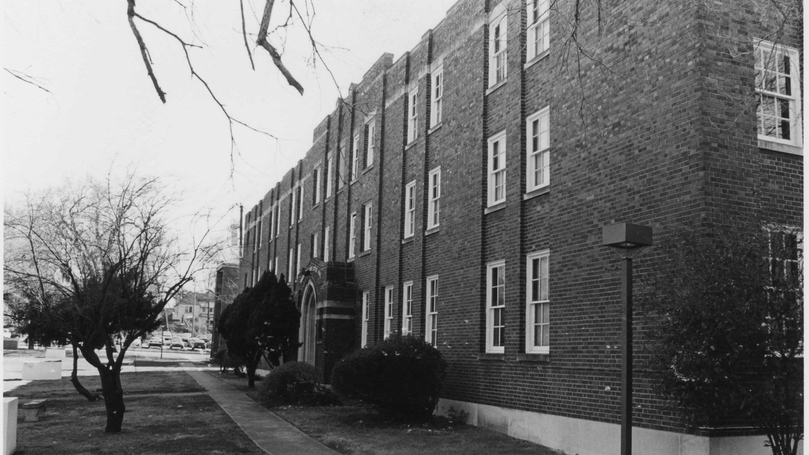 Three story brick building with tree in front yard