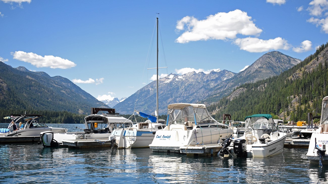 Motorboats are docked on a large lake with mountains in the background