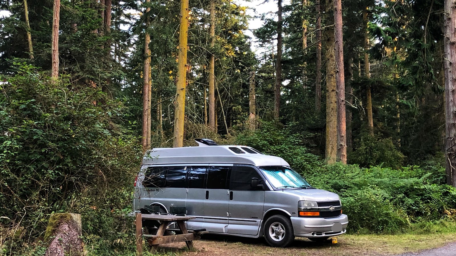 Color photograph of a camper van parked at a rustic campsite