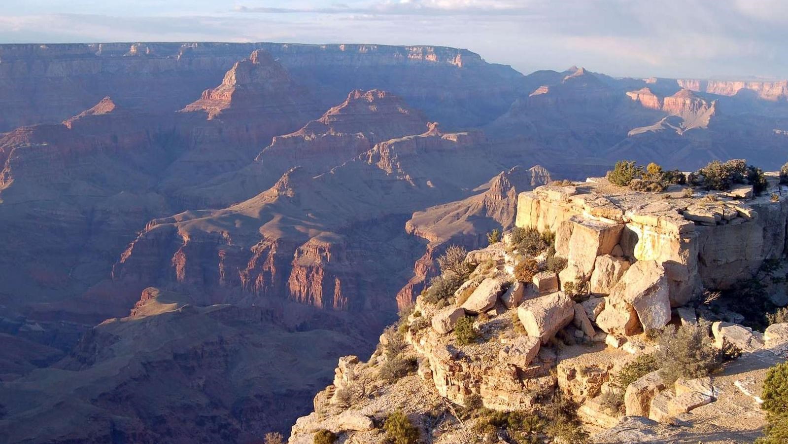 A canyon glows pink and yellow in the light of a setting sun