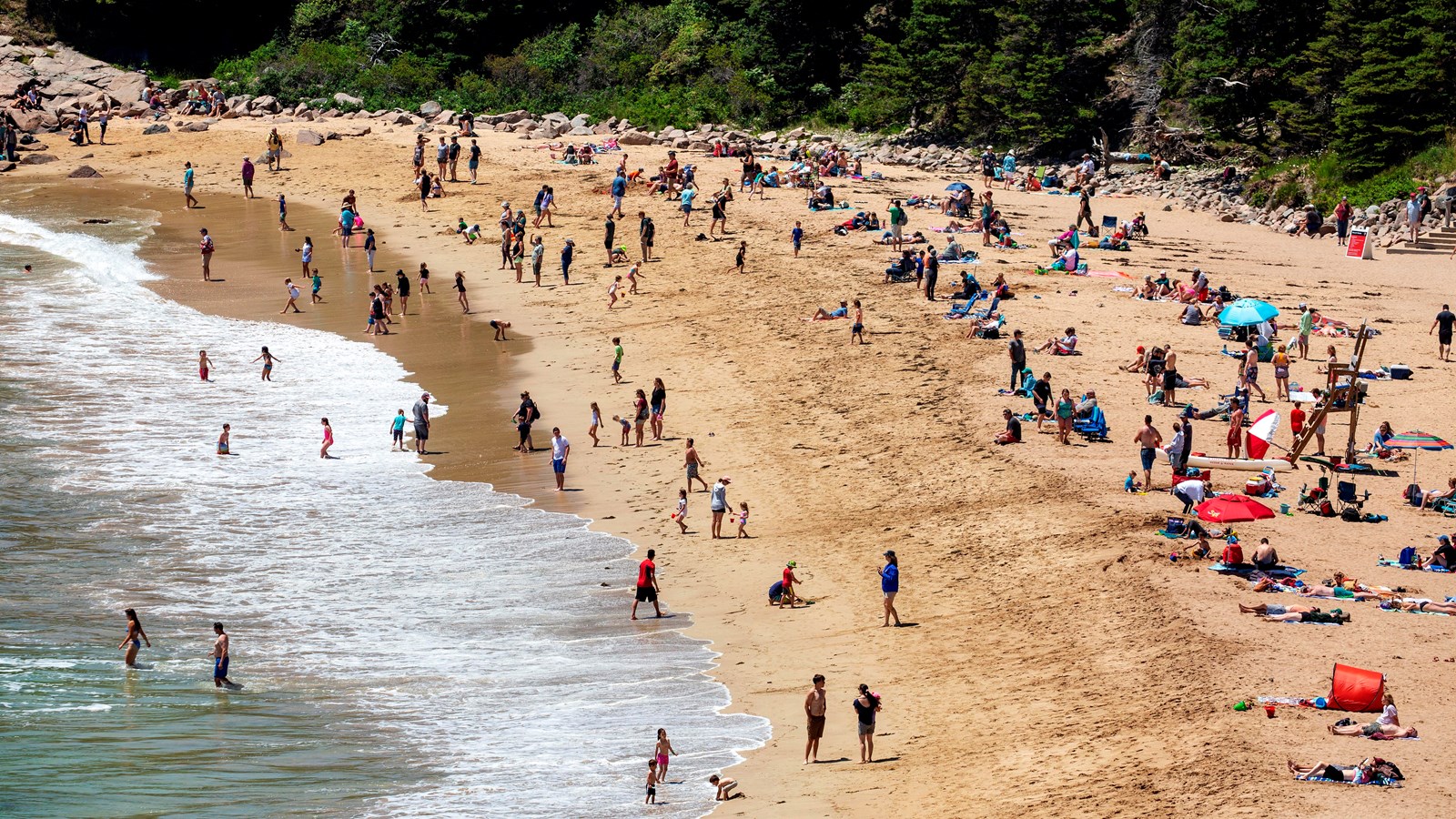 People relax and swim on a sandy beach