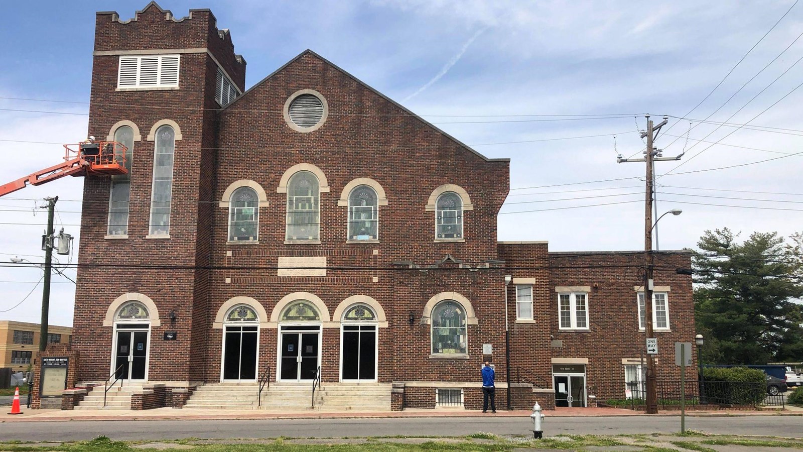 A dark-red brick church building, tower on the left, central church in the middle