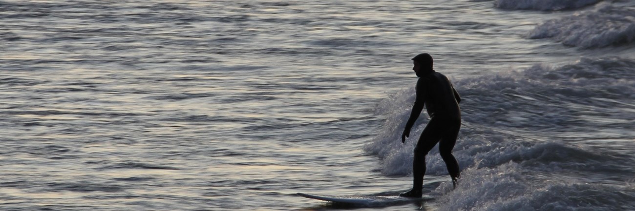 Person surfing the waves around sunset at Portage Lakefront and Riverwalk.