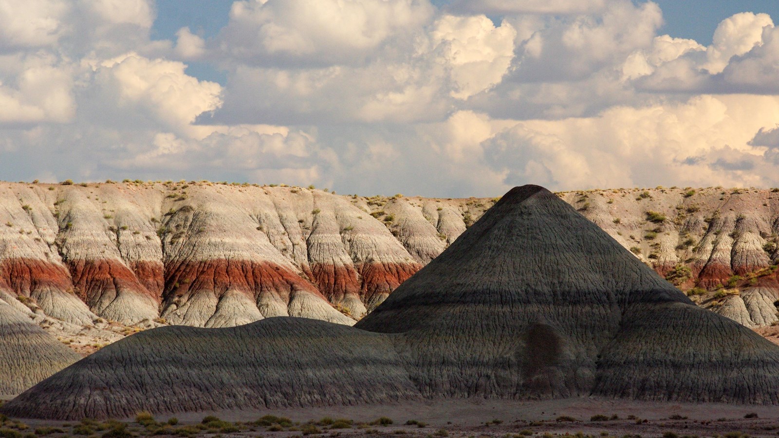 Shadowed badland against sunlit badlands under a blue sky