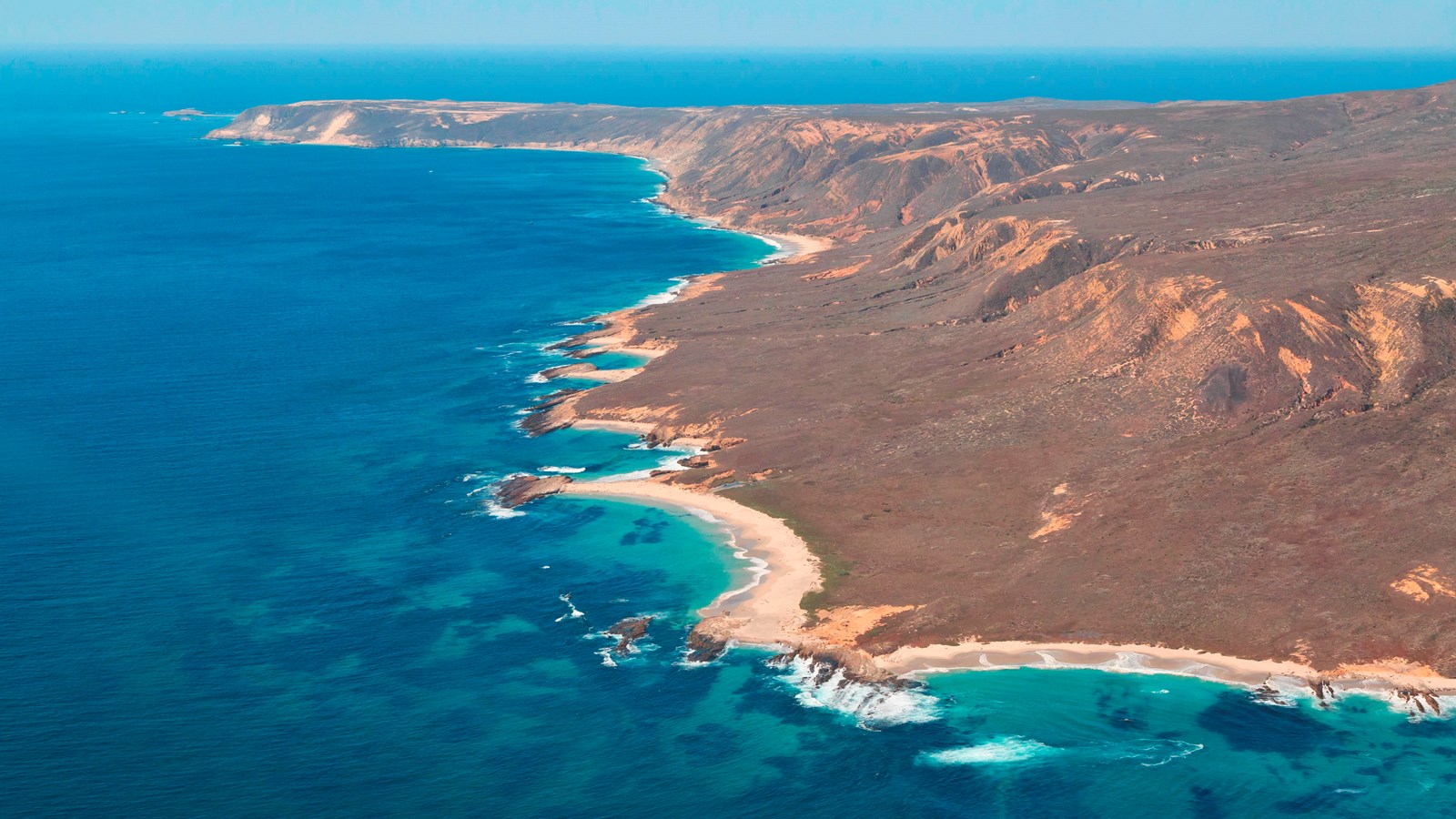 Aerial view showing flat island with jagged coastline.