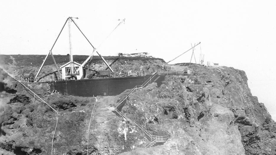 Steep cliff with stairs, buildings and boat.