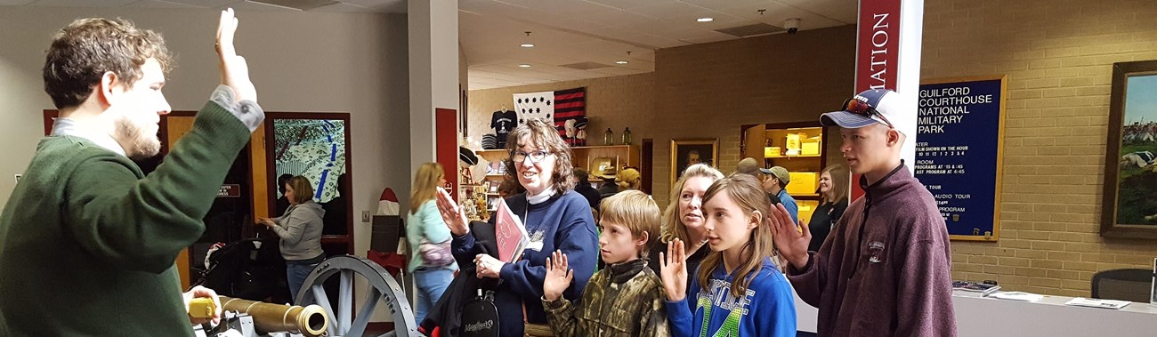 Park Ranger swears in a family of Junior Rangers next to cannon