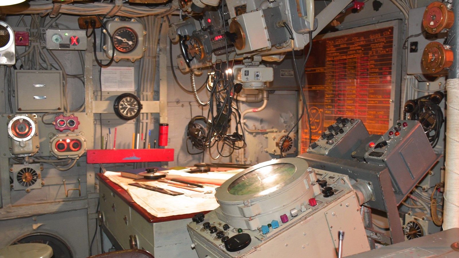 A tightly packed room with gauges, dials, lights and RADAR display units.