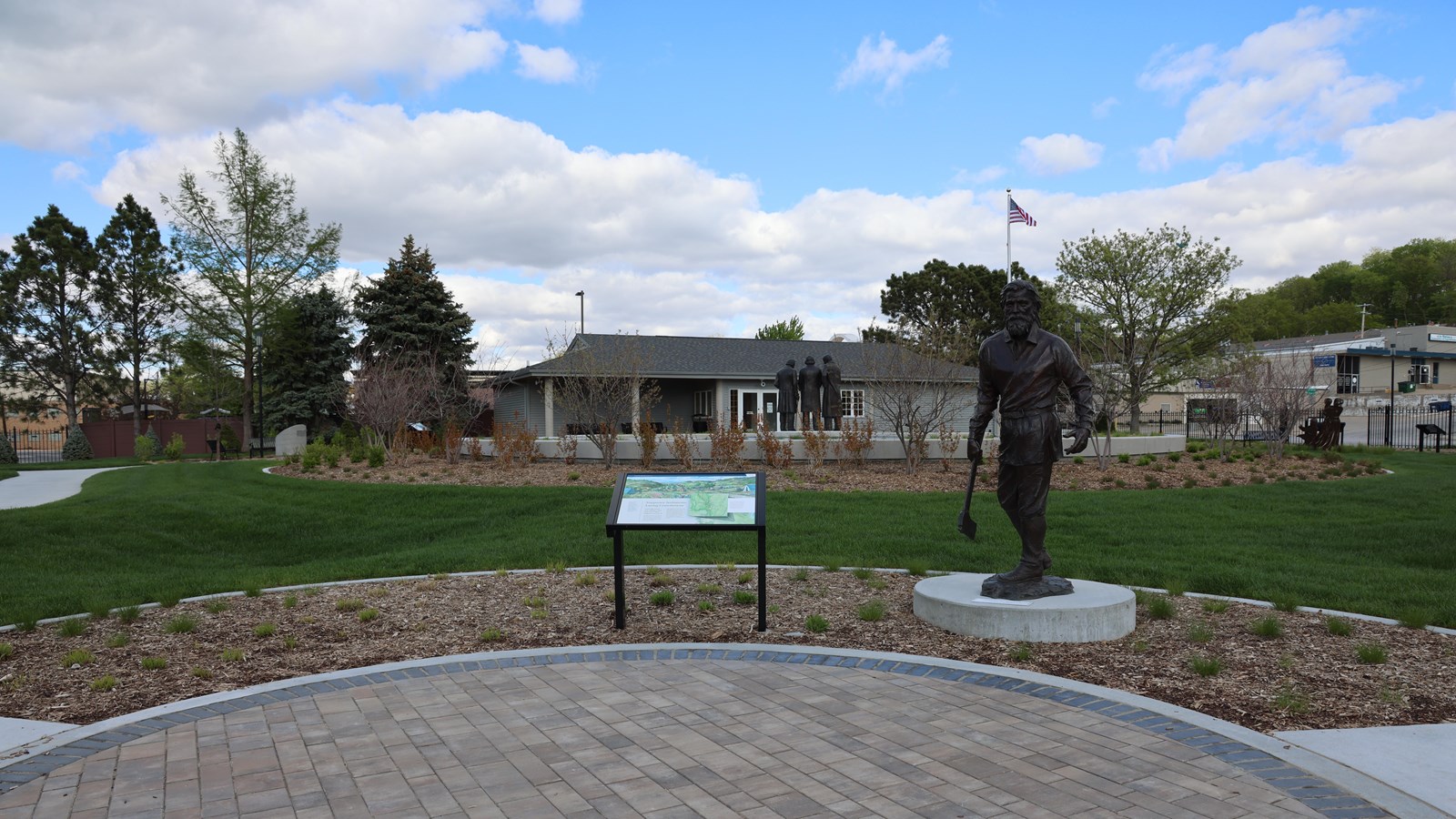 The visitor center, a one-story gray building, is beyond the grass, and a sculpture of Brigham Young