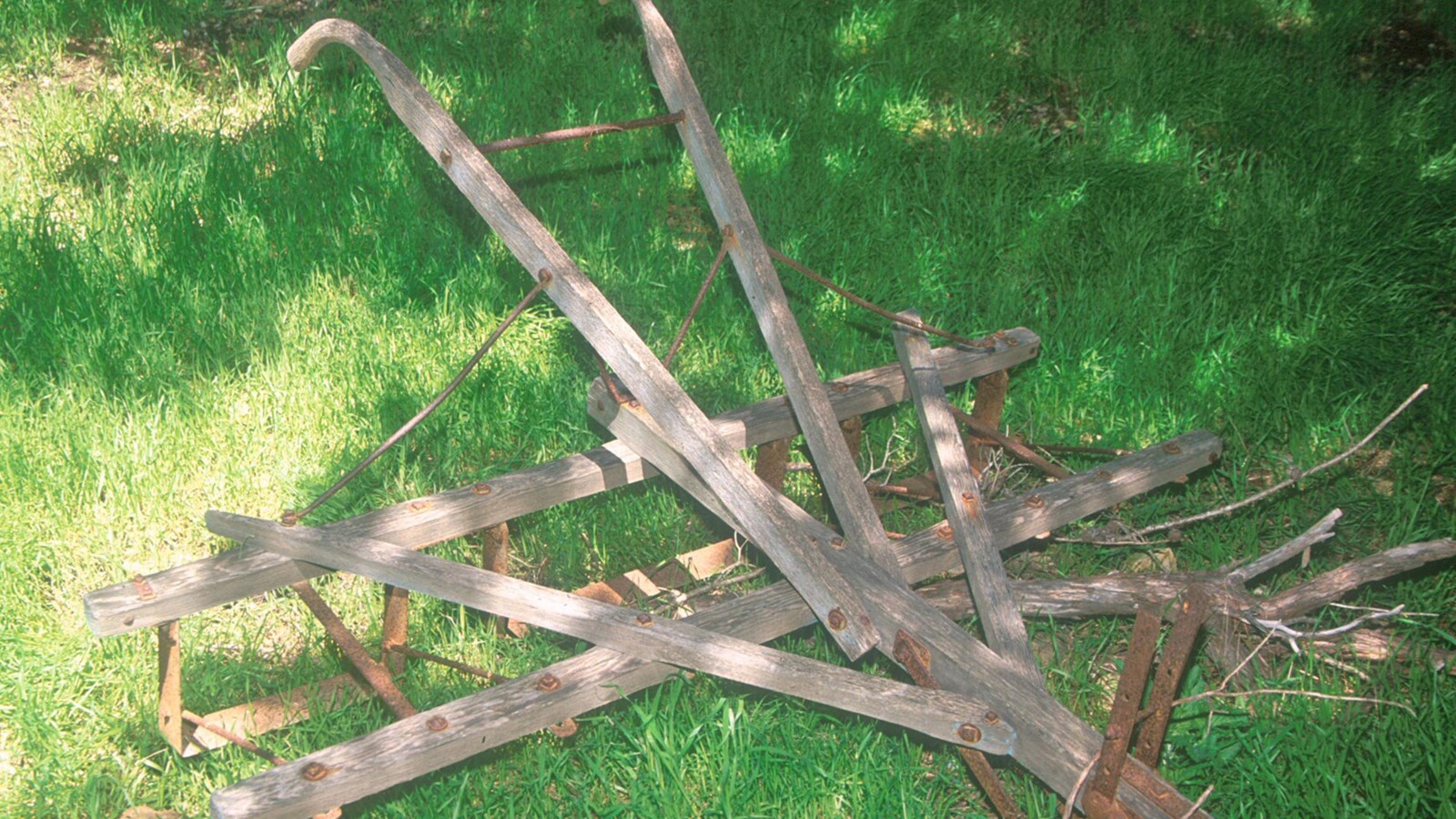 his wooden framed hand held cultivator is like a wheel barrow with a single wheel in front, triangul