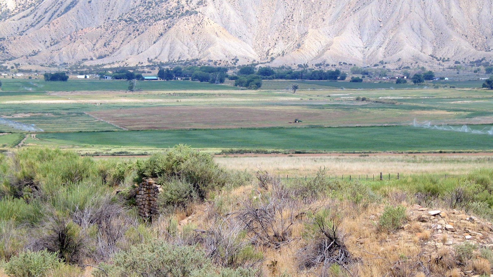 Ancient, stone-masonry wall surrounded by green farm fields.