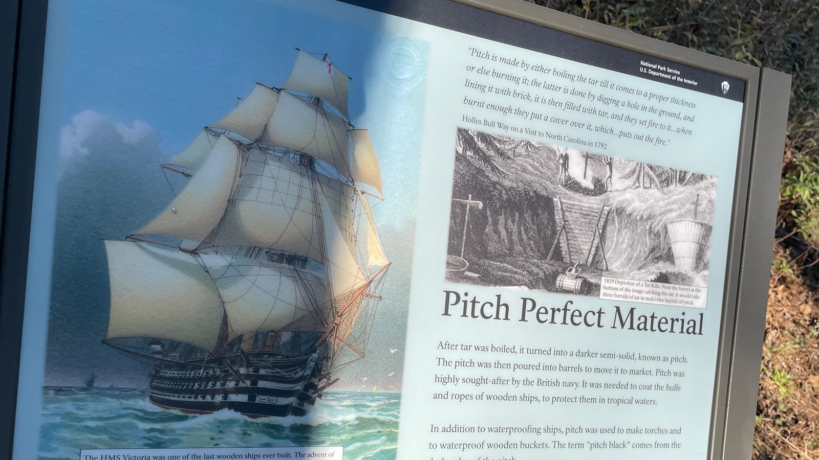 Light blue sign with images of a ship and a tar kiln.
