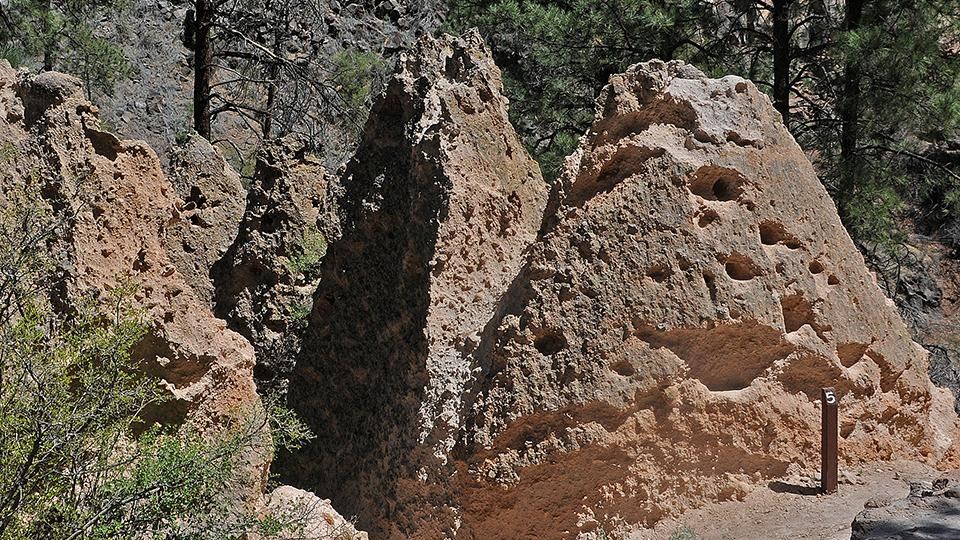 Three each-colored cones of rocks rise next to the trail, pocked with holes and cracks.