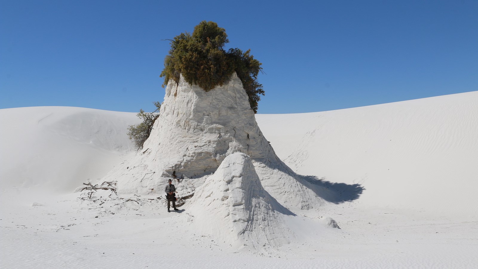 A ranger stands at the forefront of a large gypsum sand pedestal.