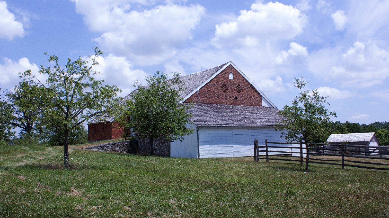 A brick bank barn with a hole near the roof caused by a shell