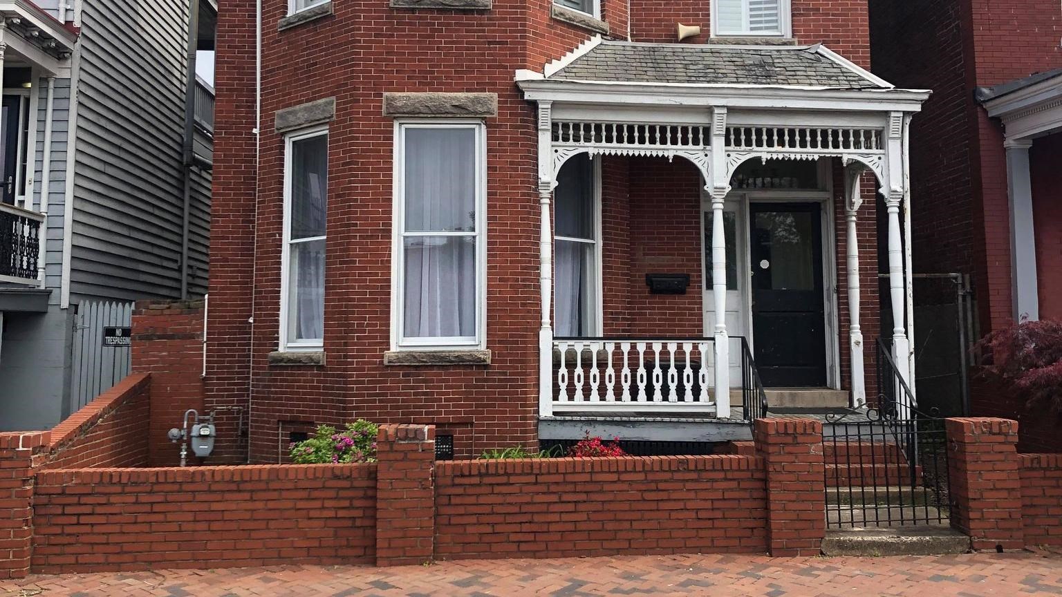 A red-brick two story home, a two foot brick wall surrounds the home and yard.