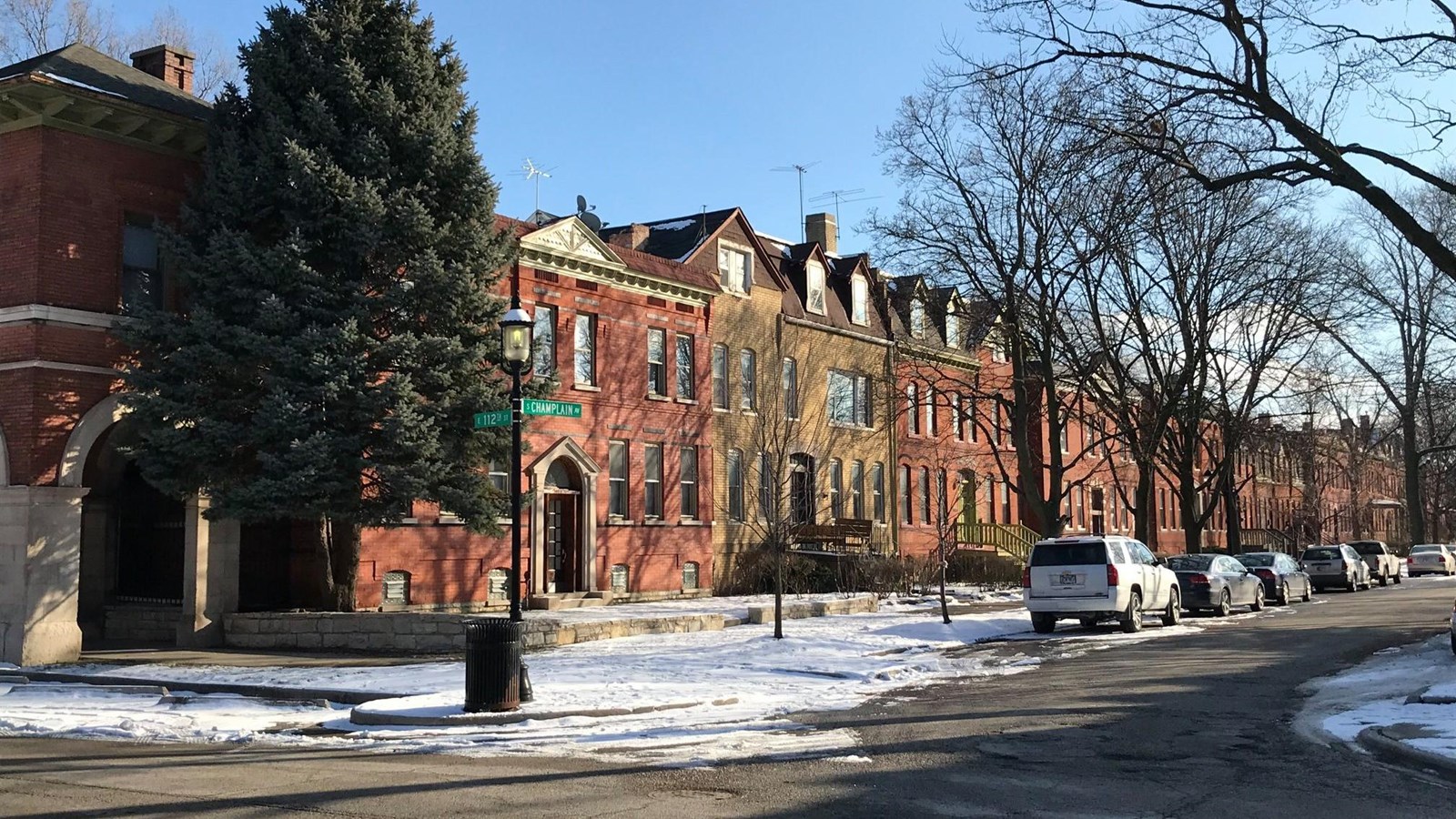 Brick row houses with snow covering their front yards.