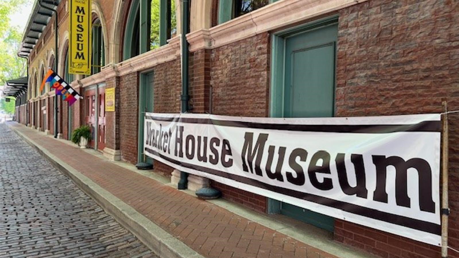 Front of a brick building with large arched windows and a museum sign.