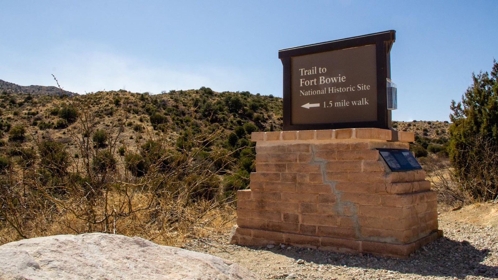 A brown wooden park sign, with mountains in the background