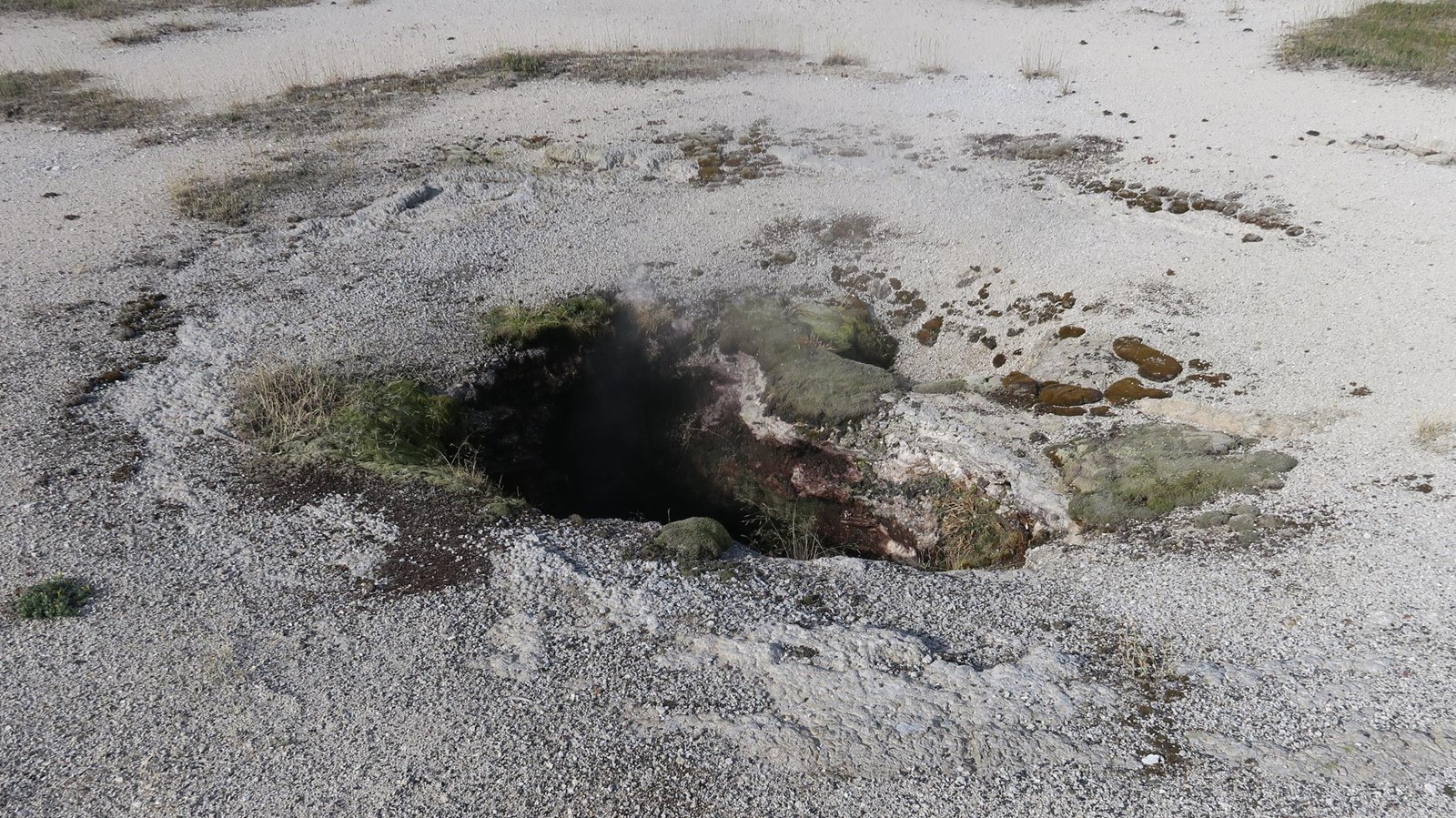 A cavernous opening in the ground surface that is continuously steaming.