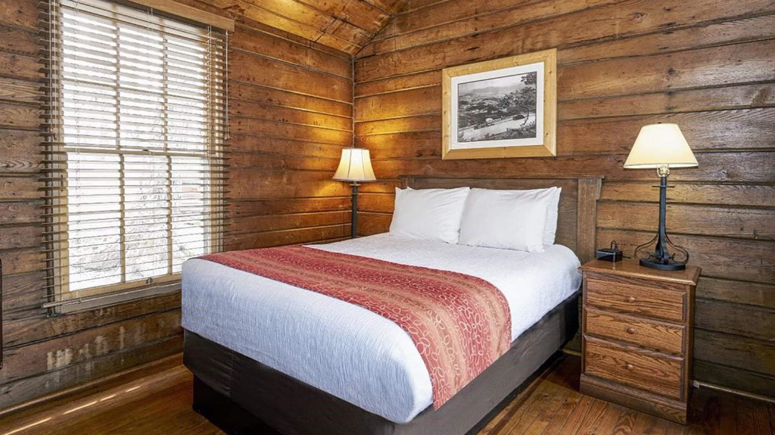 The interior of a rustic cabin with wood walls and a bed.