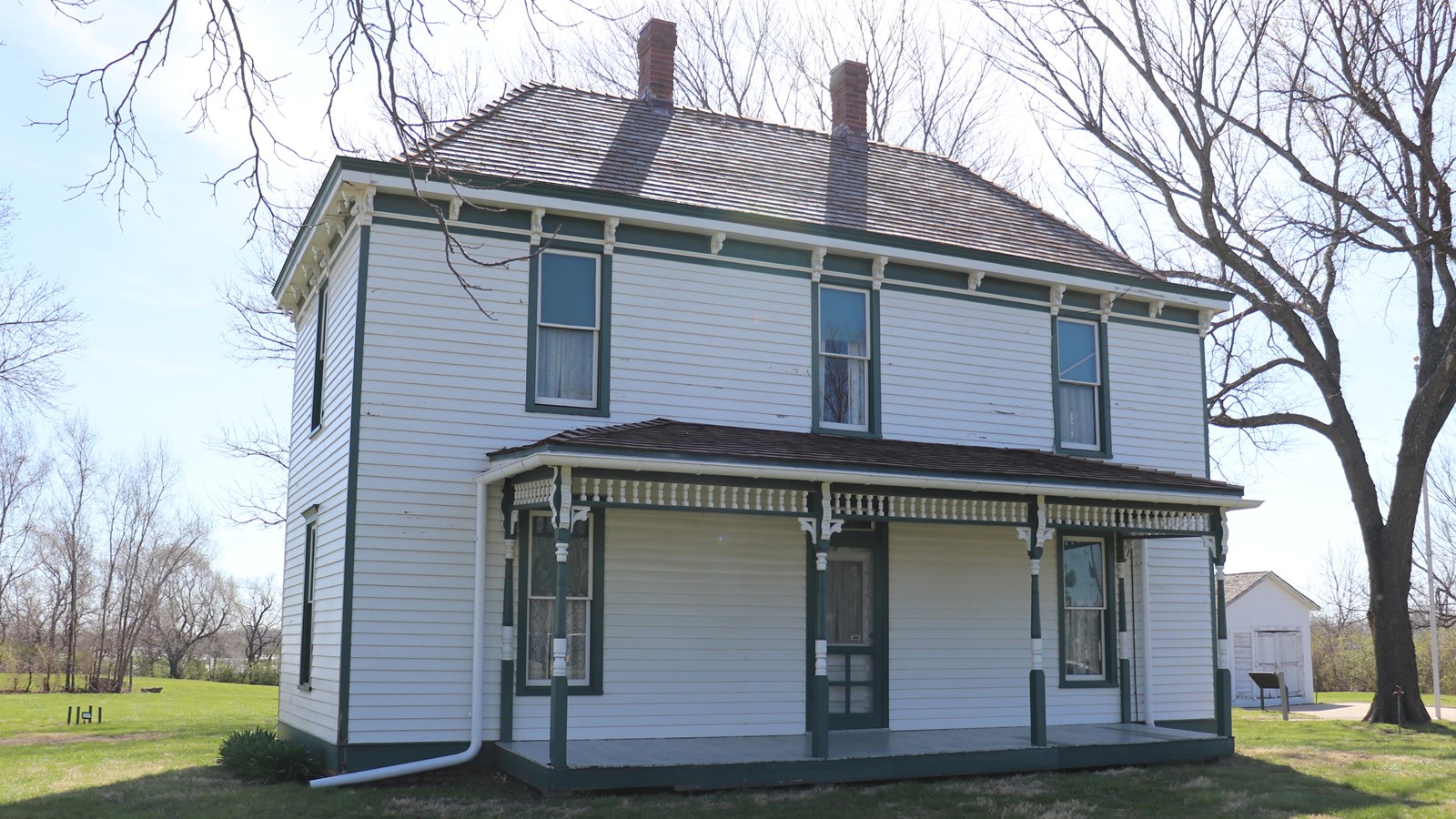 The white two-story Truman home with front porch and green trim.