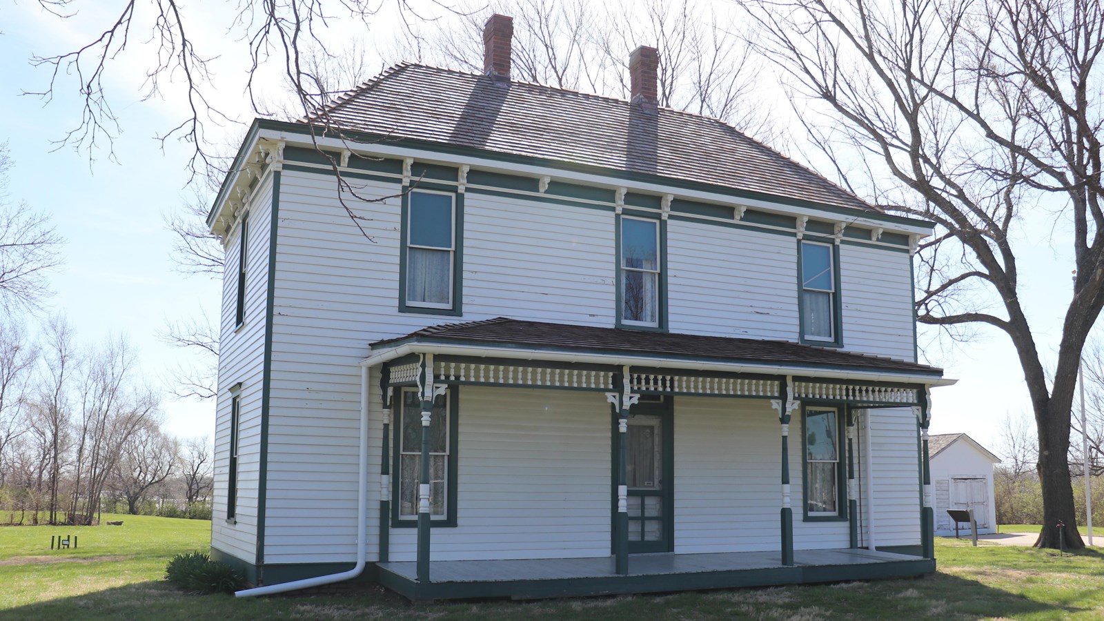 The white two-story Truman home with front porch and green trim. 