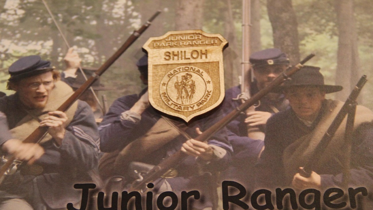 A wooden Junior Ranger Badge sits on Junior Ranger booklet