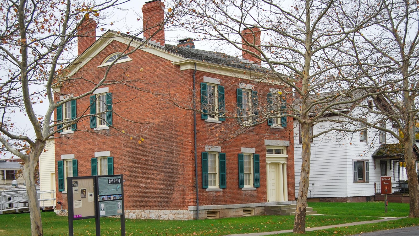 A two-story brick house with a tree in the yard