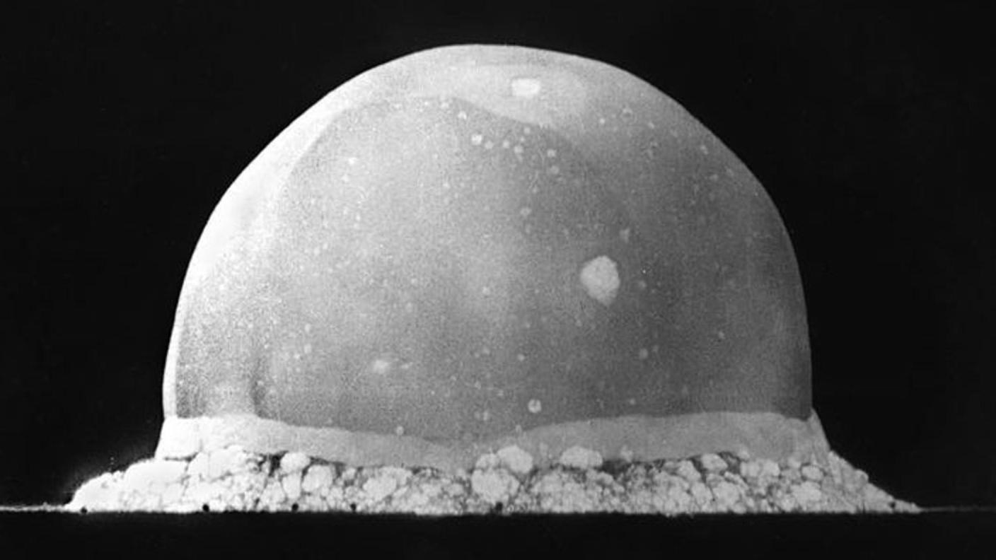 A black and white photo of an explosion and fireball shooting upwards in a dome