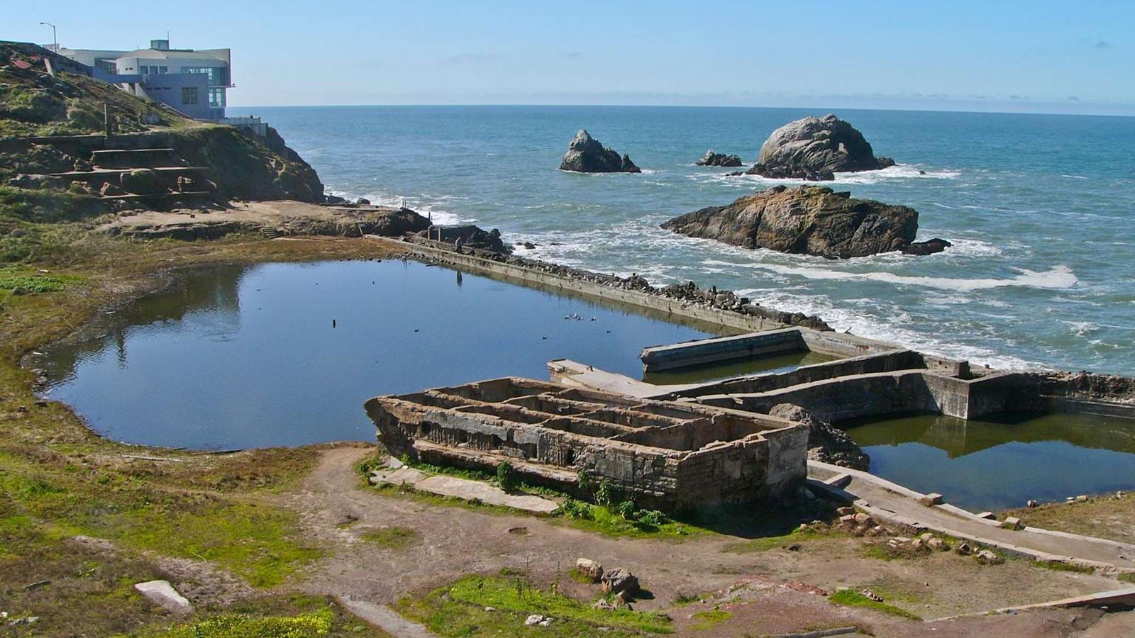 The waterlogged ruins of Sutro Baths along the water\'s edge.