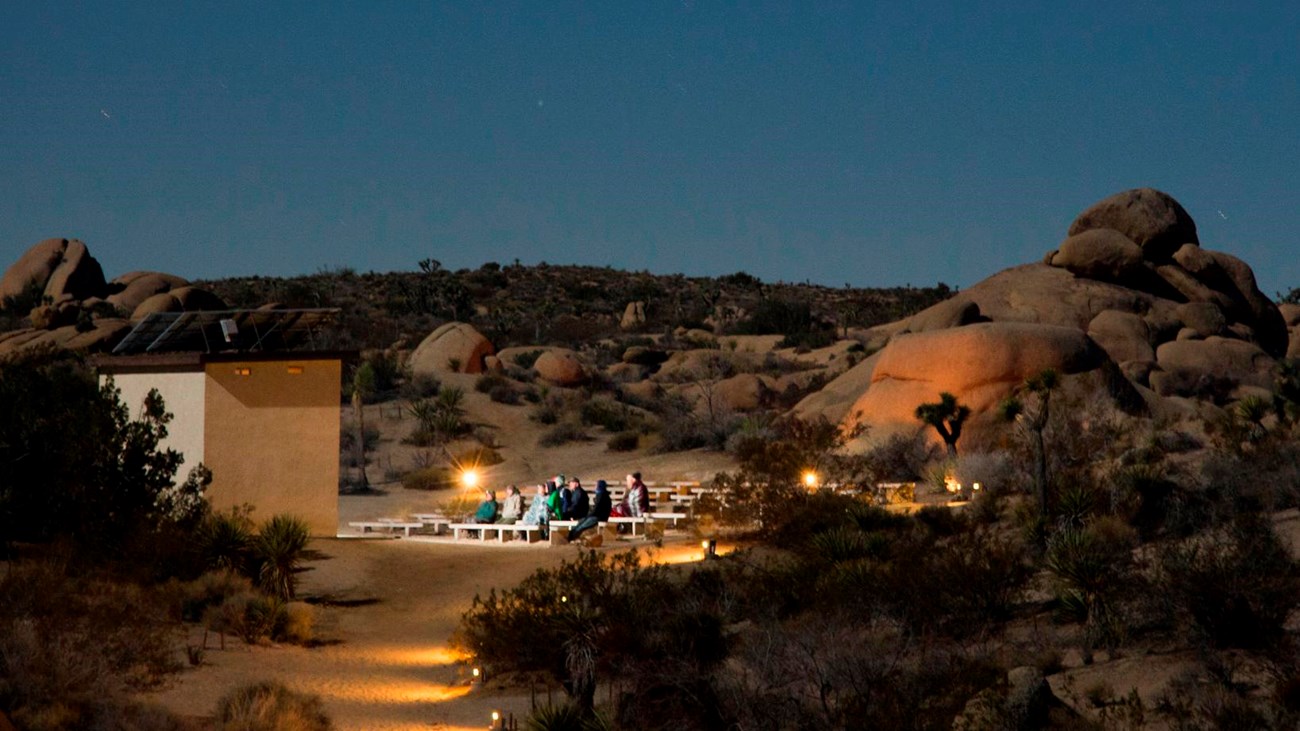 A small amphitheater is surrounded by boulders and desert shrubs.  