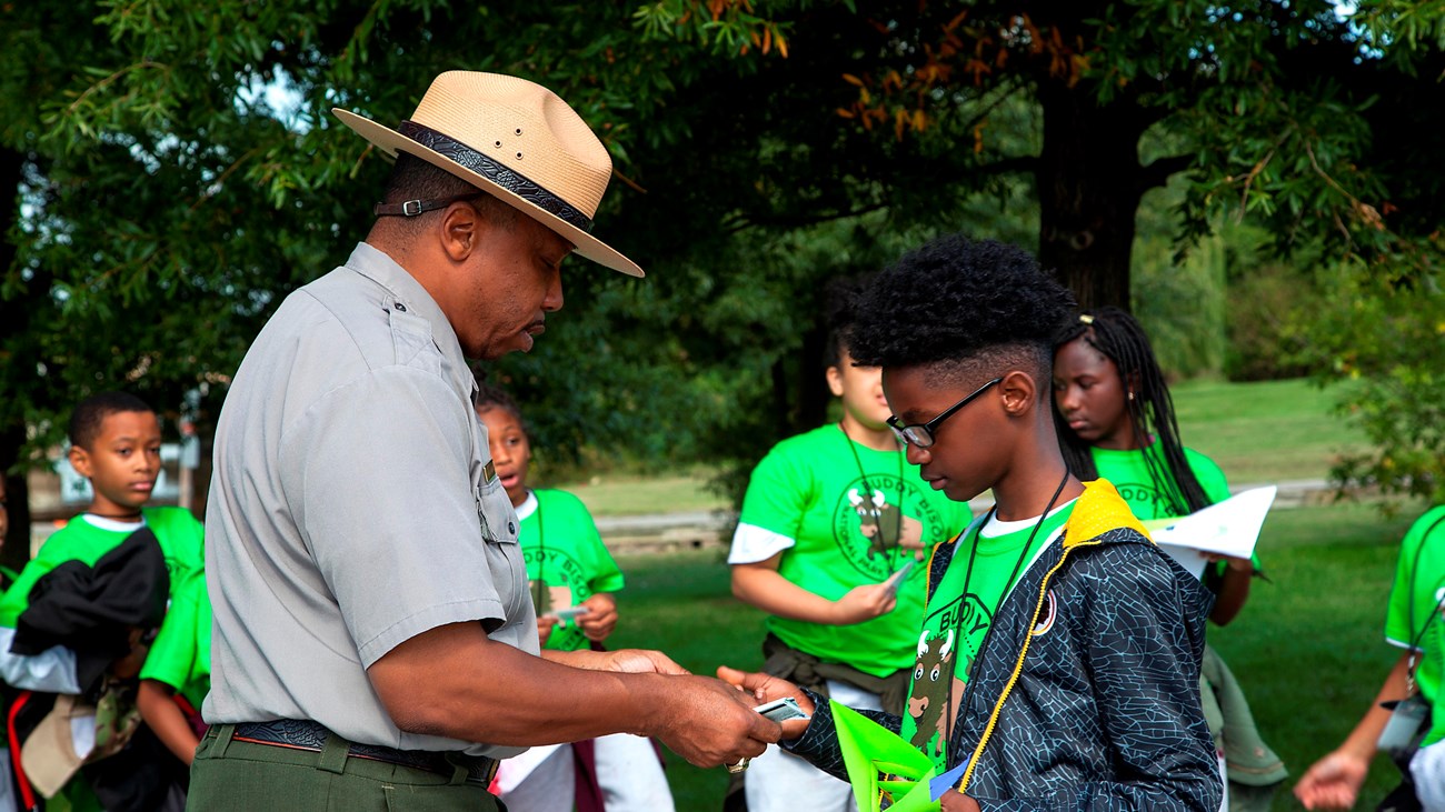 A park ranger hands a 4th grader his Junior Ranger badge.
