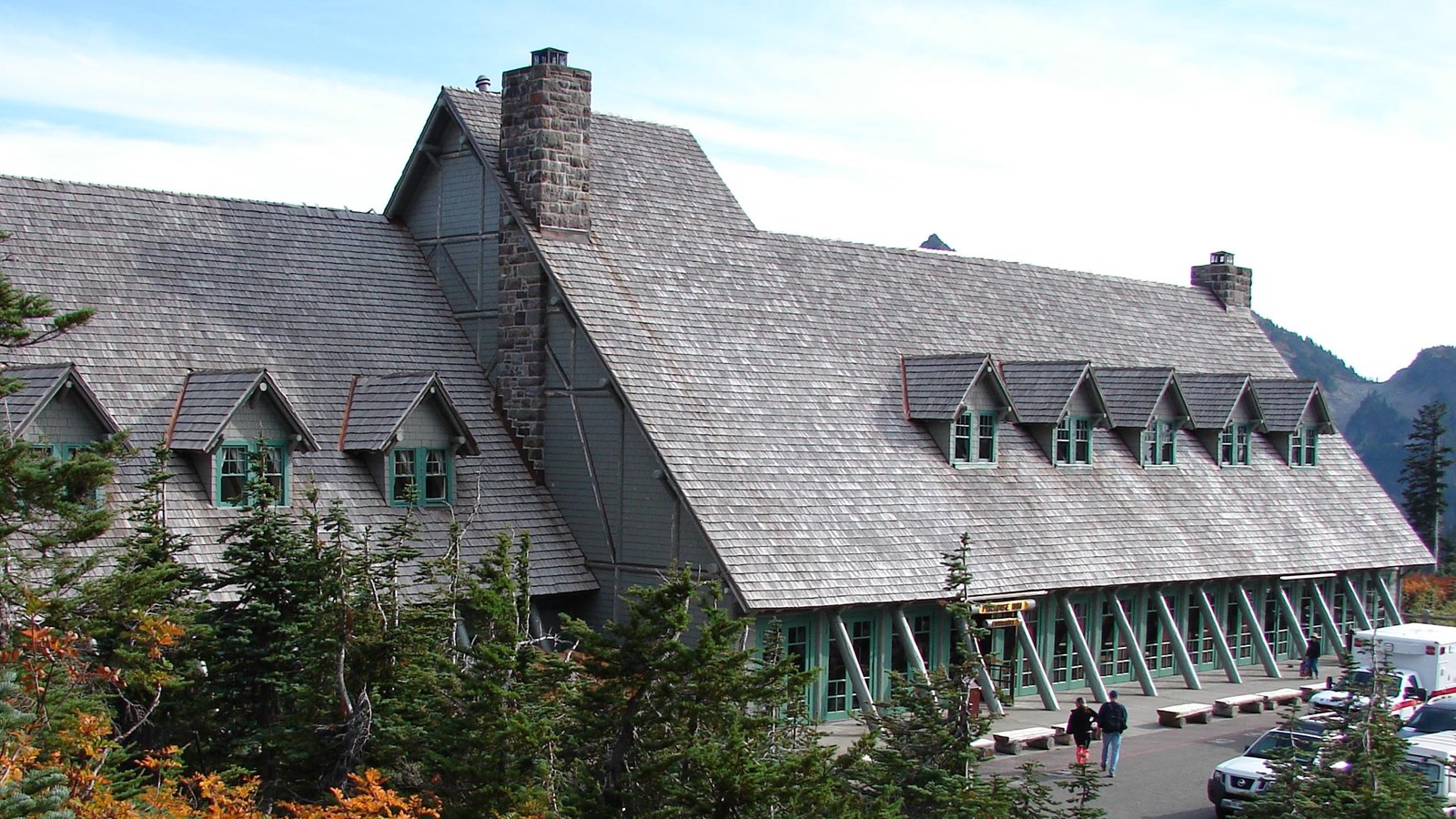 A rustic gray building with green trim sits surrounded by fall foliage.