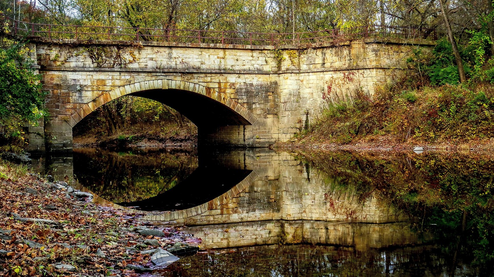 A single arch aqueduct spans a creek.