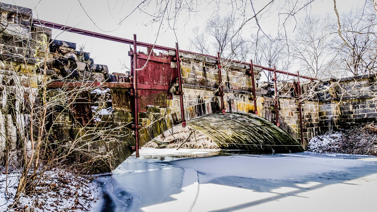 A single arch aqueduct spans a creek. 