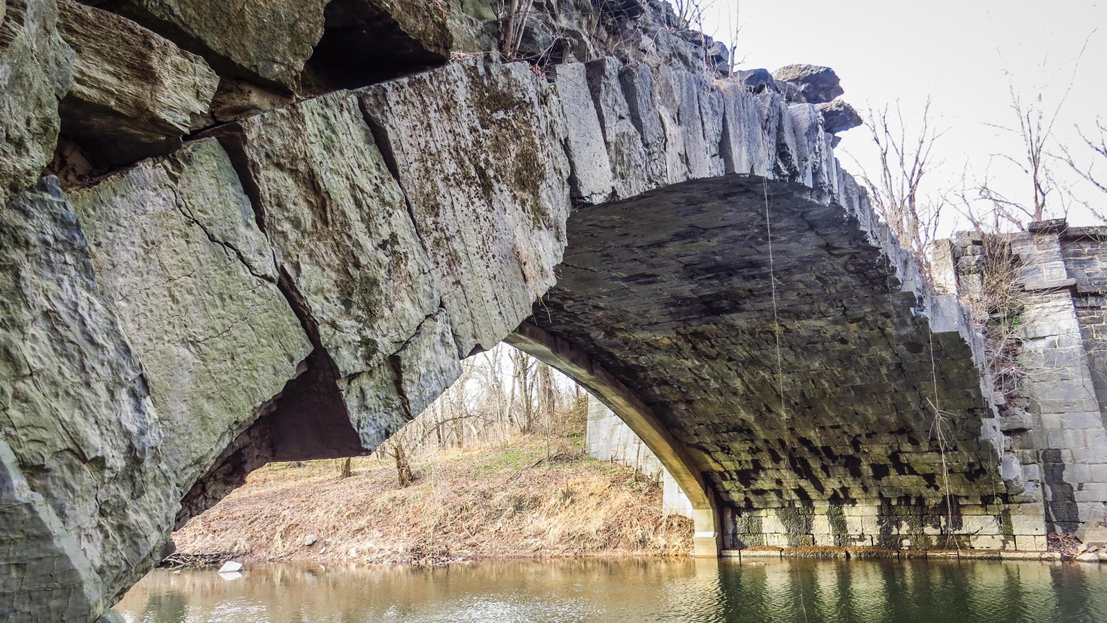 A single arch aqueduct spans a creek.