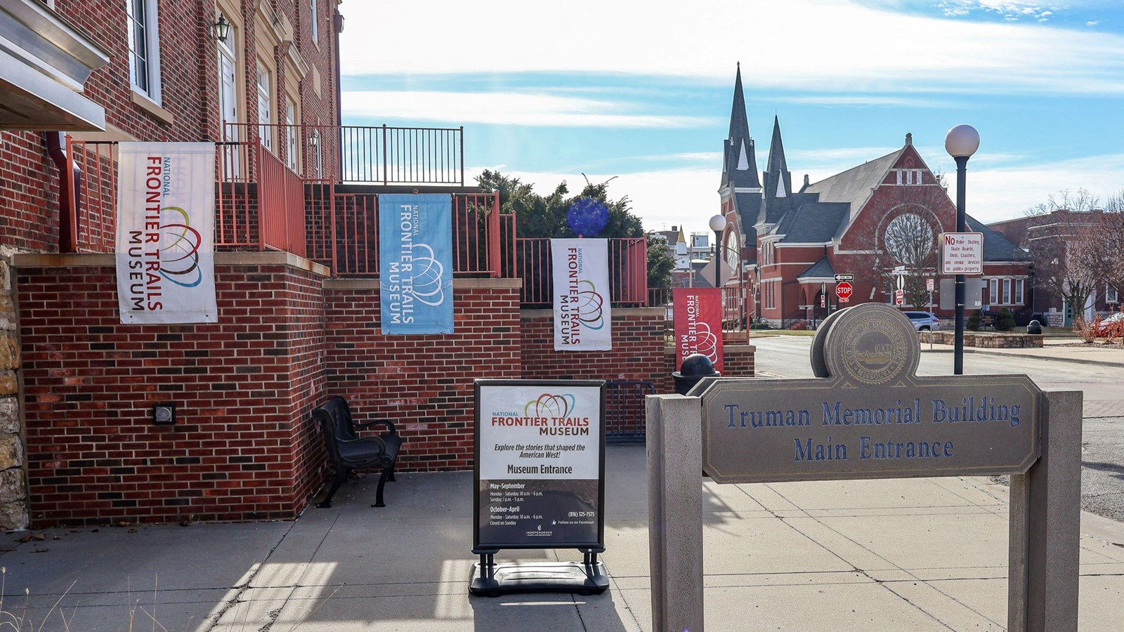 Signs hang outside a brick building entrace to a museum.