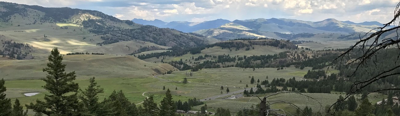 View of a valley and surrounding mountains from atop a hill.