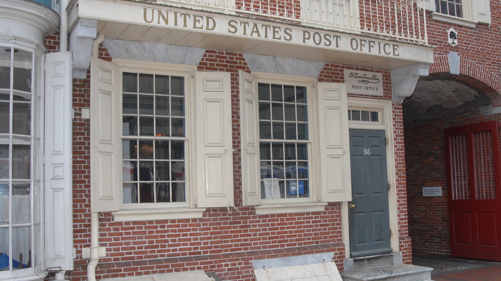 Exterior view of first floor of brick rowhouse with the words 