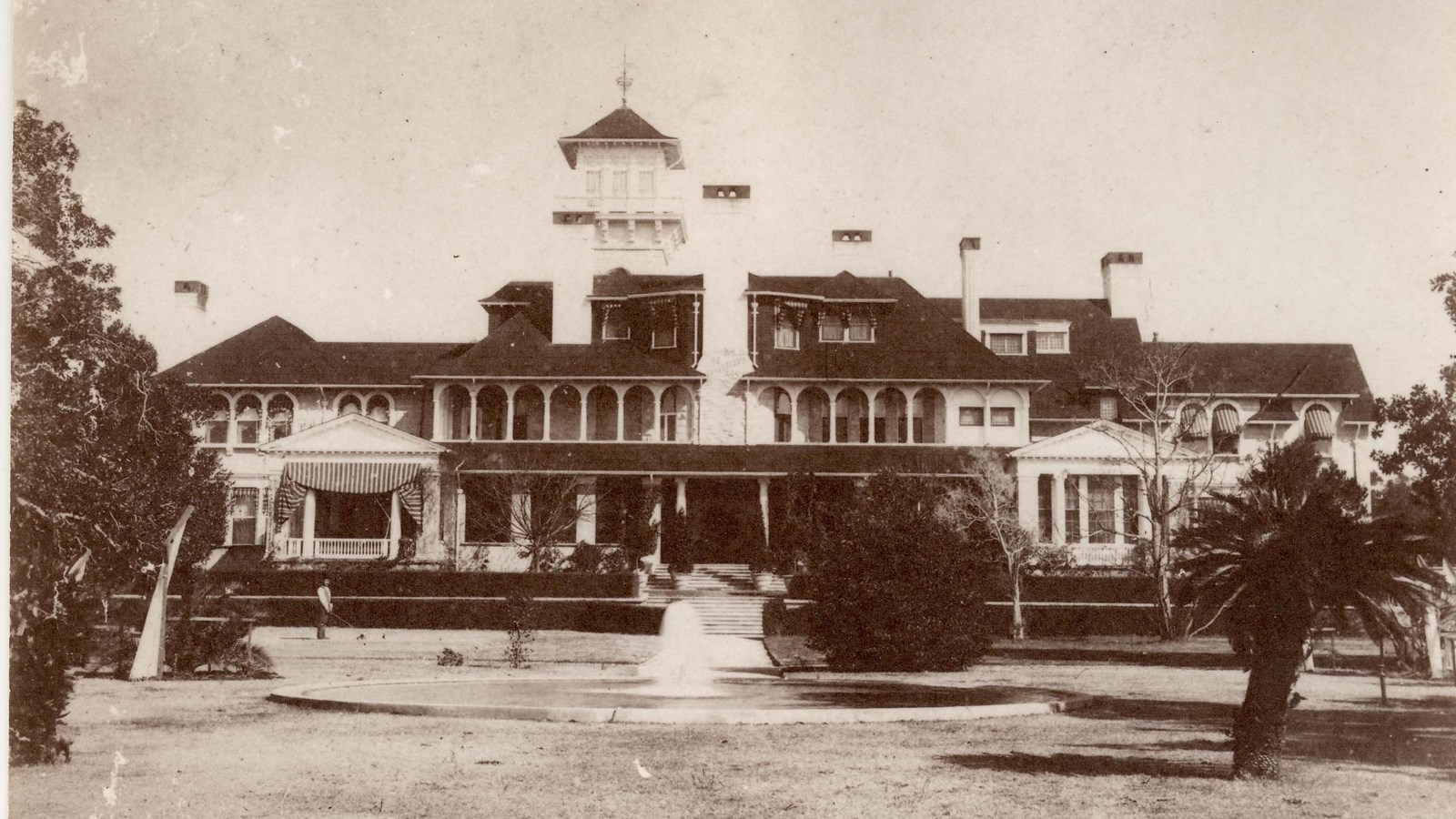Black and white of mansion with chimneys, observation tower, and lawn