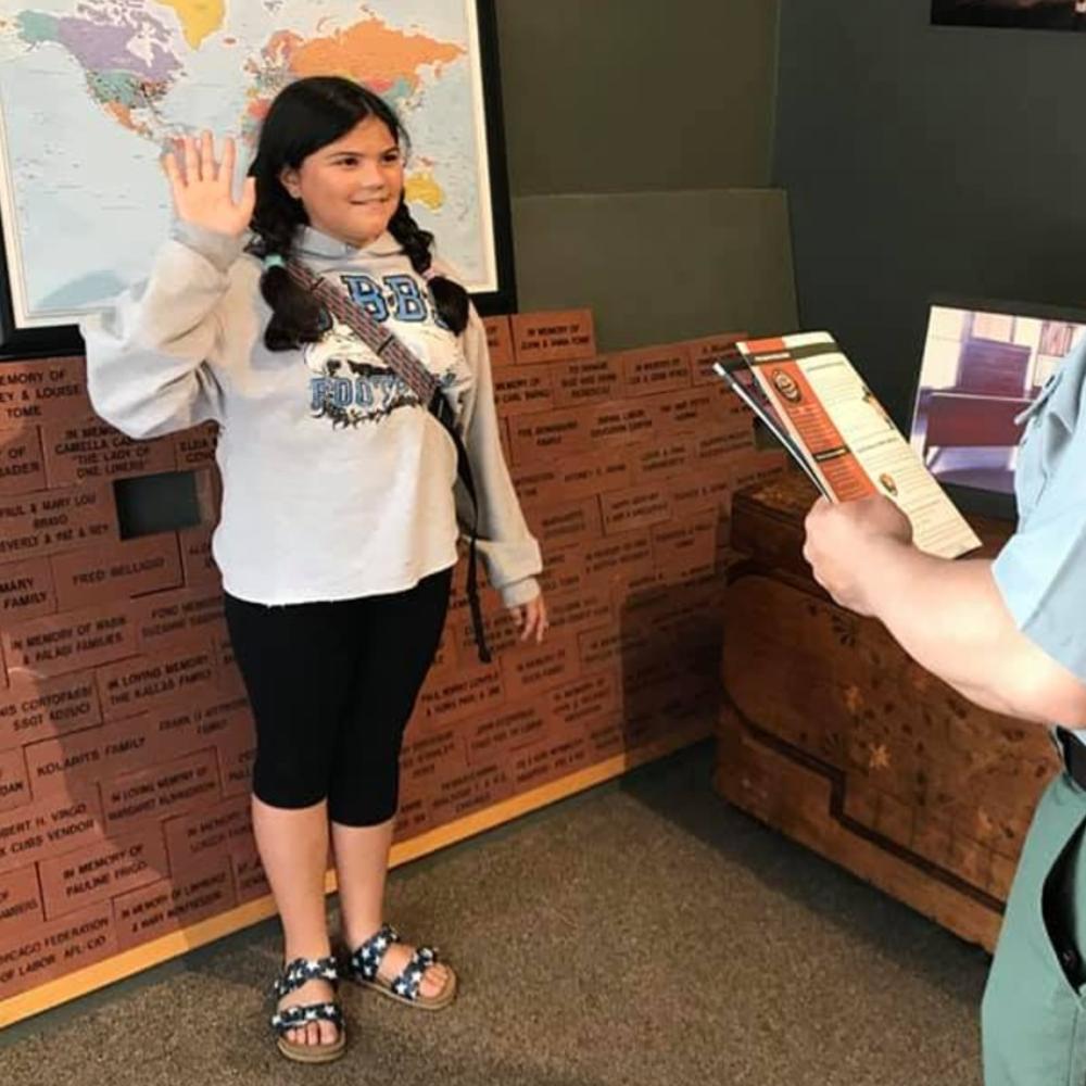 A girl is sworn in by a park ranger as a junior ranger