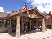 several people stand by the entrance to a modern lodge with a gabled roof