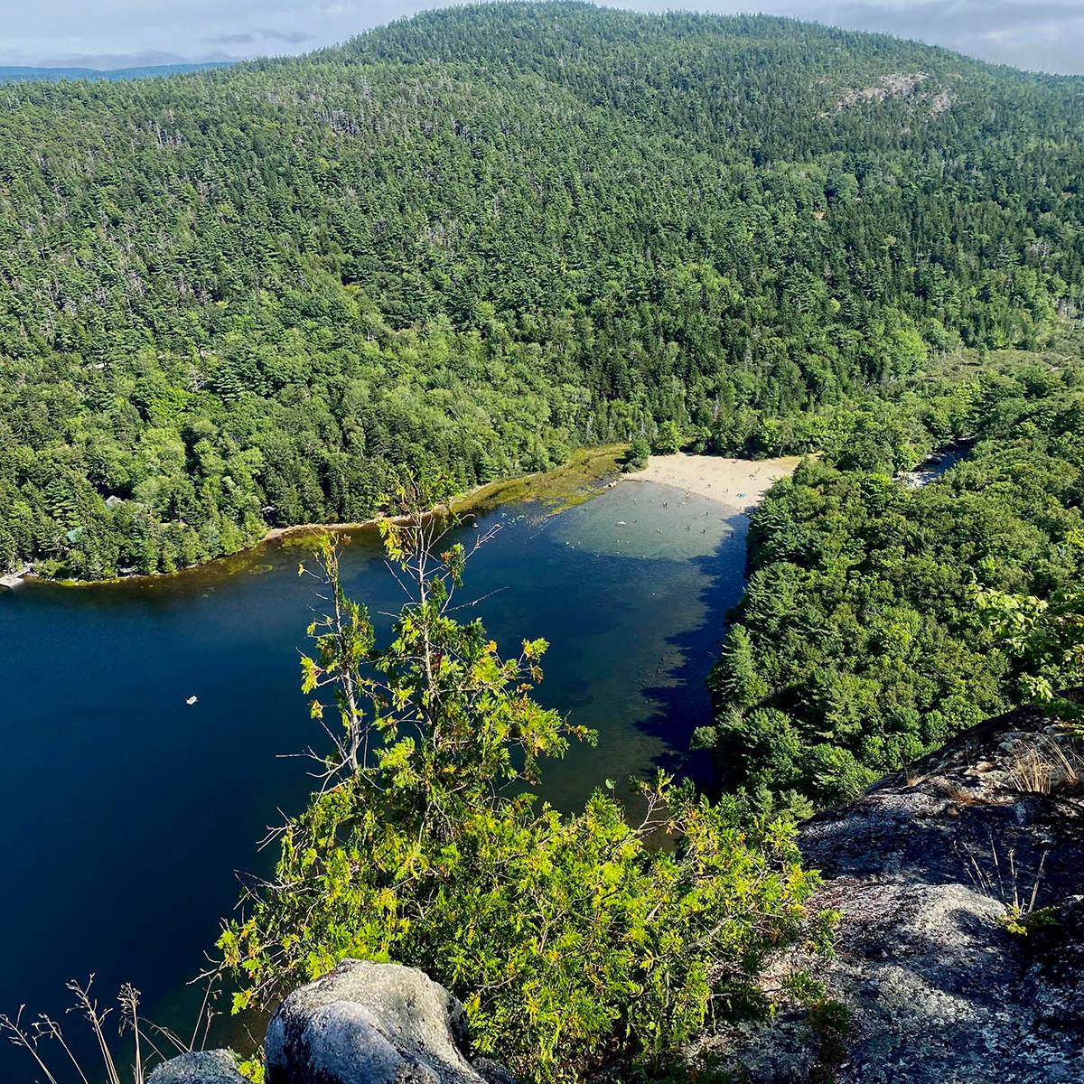 Echo Lake and Beach are nestled at the bottom a mountain ridge while granite cliffs rise steeply.