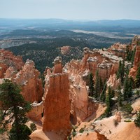 A landscape of red rocks in the foreground with hazy mountains on the horizon