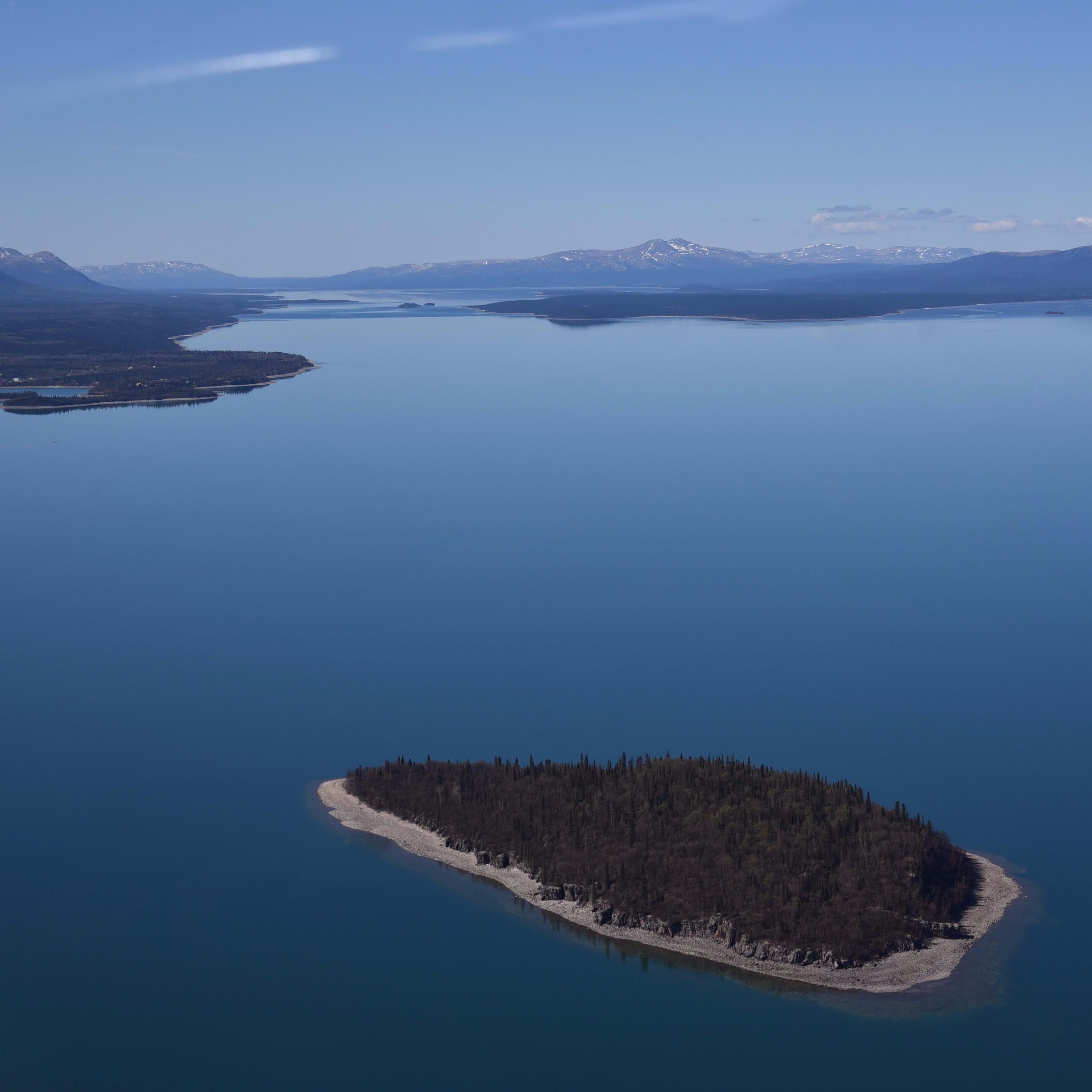 An aerial view of an island in the blue waters of Lake Clark
