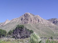 A large peak rises above a desert mountain landscape
