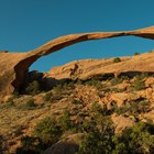 a broad, narrow arch with rock piles beneath and a blue sky above