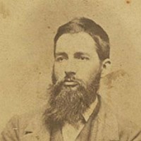 An 1800s portrait photo shows a long-bearded young man in a suit.