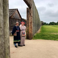 The gates of Fort Vancouver with two women in 1840s style clothing standing in front.